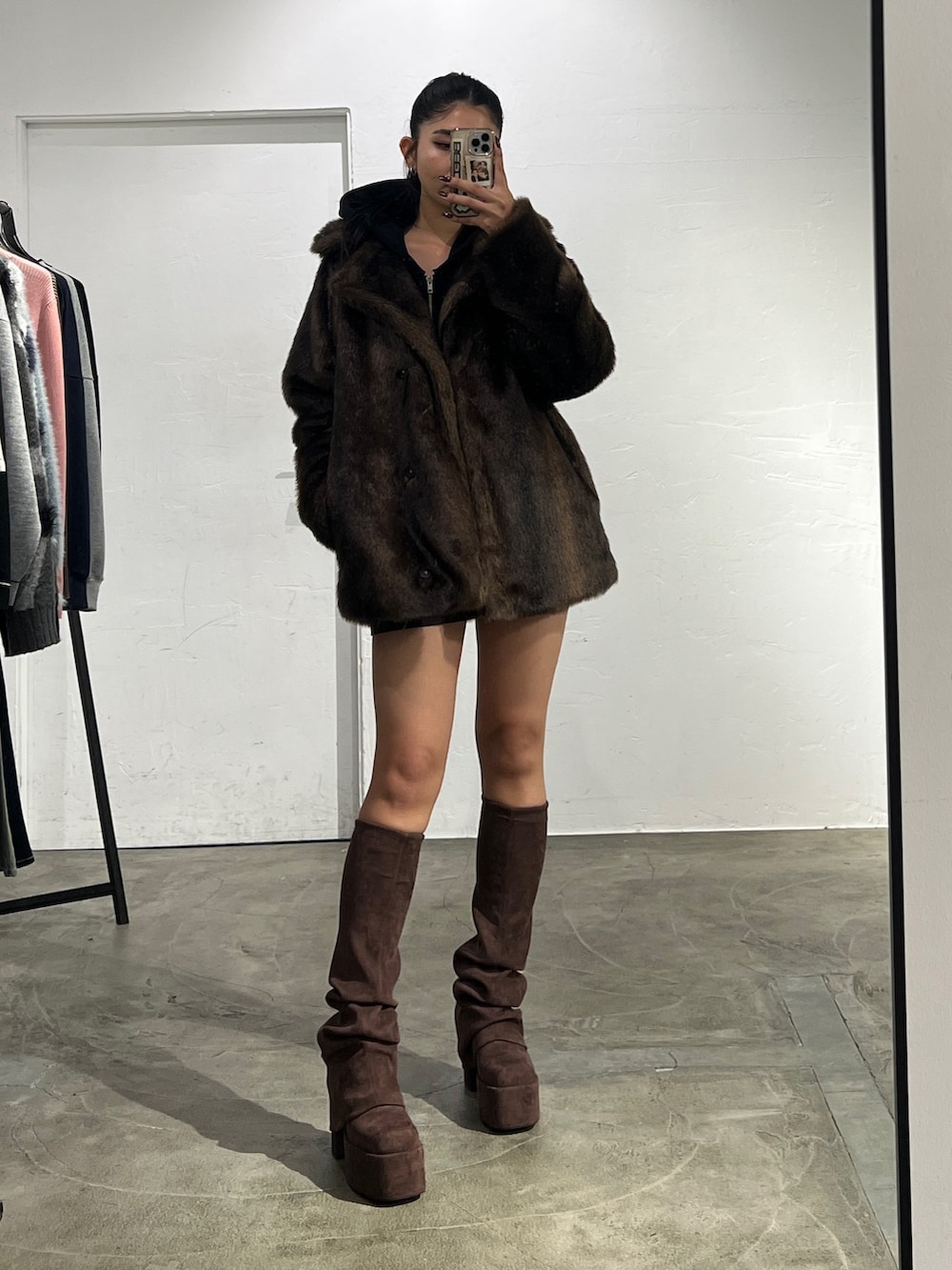 ブラック系のパーカー、ブラウン系のスカート、ブラウン系のブーツを着用したレディースの秋コーディネートの3枚目の写真