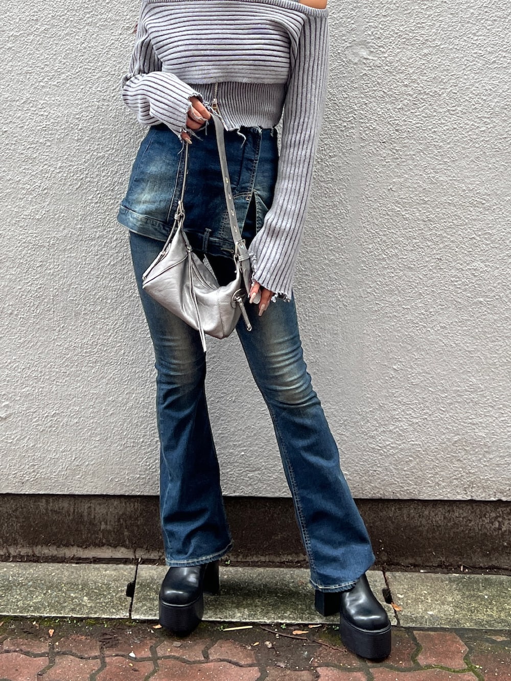 グレー系のニット/セーター、ブルー系のデニムパンツ、シルバー系のハンドバッグを着用したレディースの秋コーディネートの5枚目の写真
