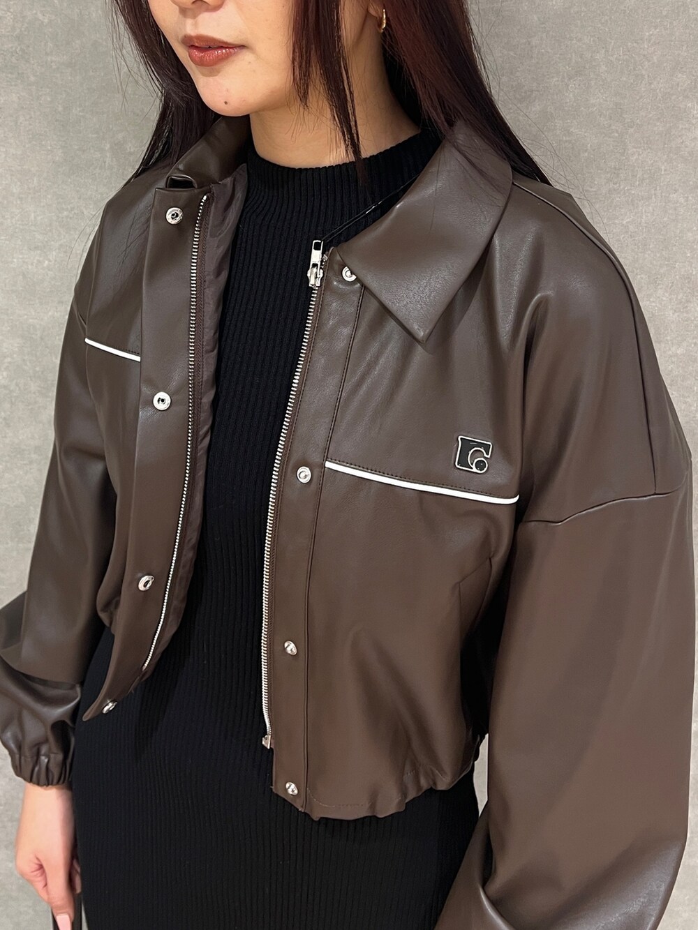 ブラウン系のブルゾン、ブラック系のワンピース、ブラック系のハンドバッグを着用したレディースの冬コーディネートの4枚目の写真