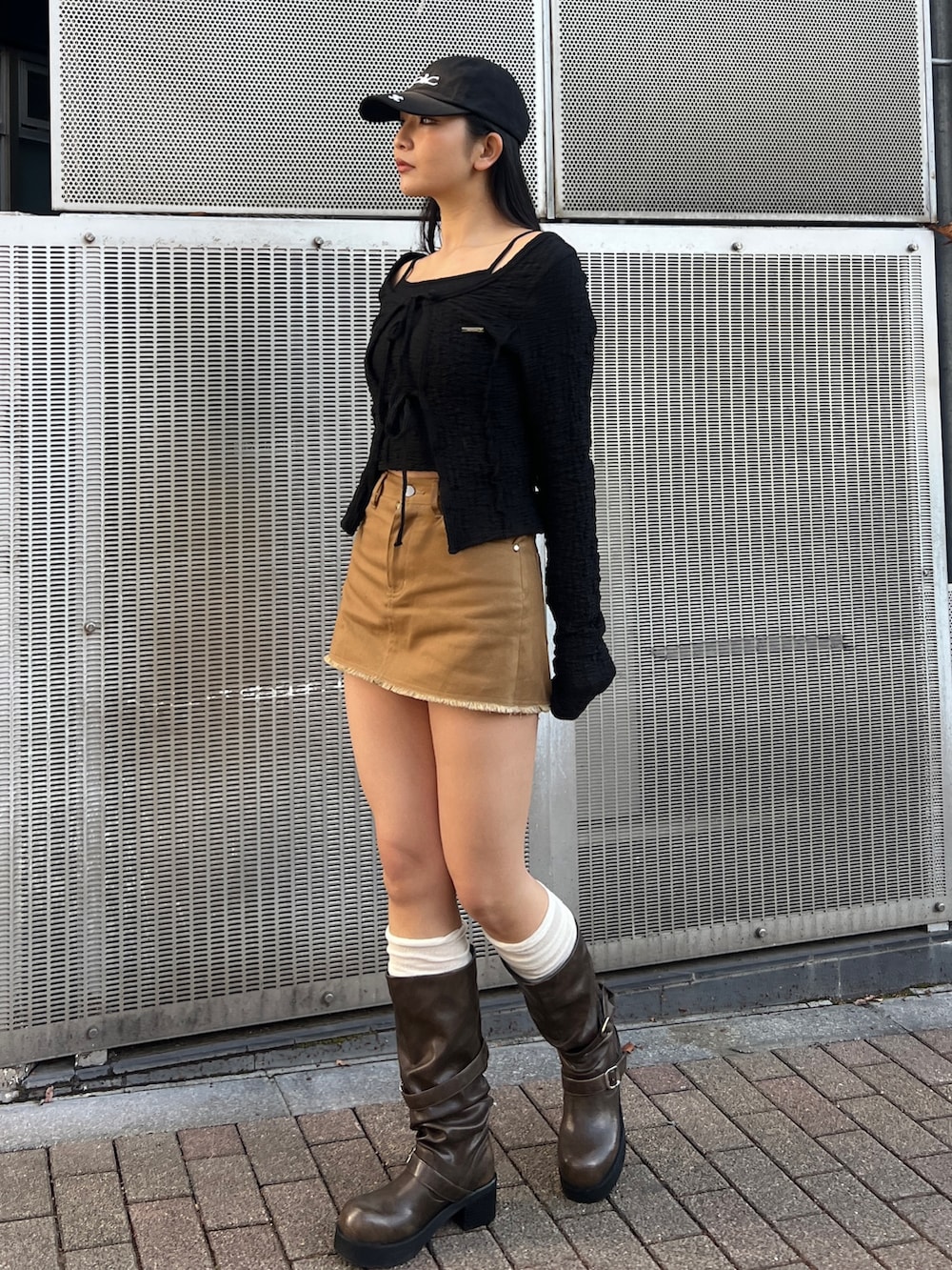 ブラック系のTシャツ/カットソー、ブラウン系のブーツ、ブラック系のキャップを着用したレディースの冬コーディネートの2枚目の写真