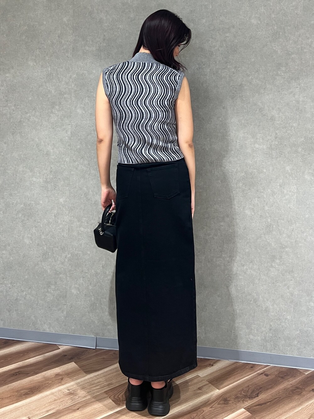 グレー系のタンクトップ、ブラック系のデニムスカート、ブラック系のハンドバッグを着用したレディースの夏コーディネートの5枚目の写真