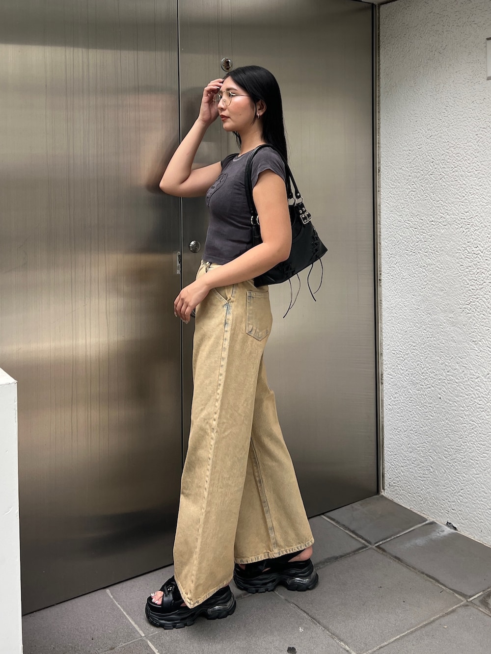 ブラック系のTシャツ/カットソー、ベージュ系のデニムパンツ、ブラック系のサンダルを着用したレディースの夏コーディネートの2枚目の写真
