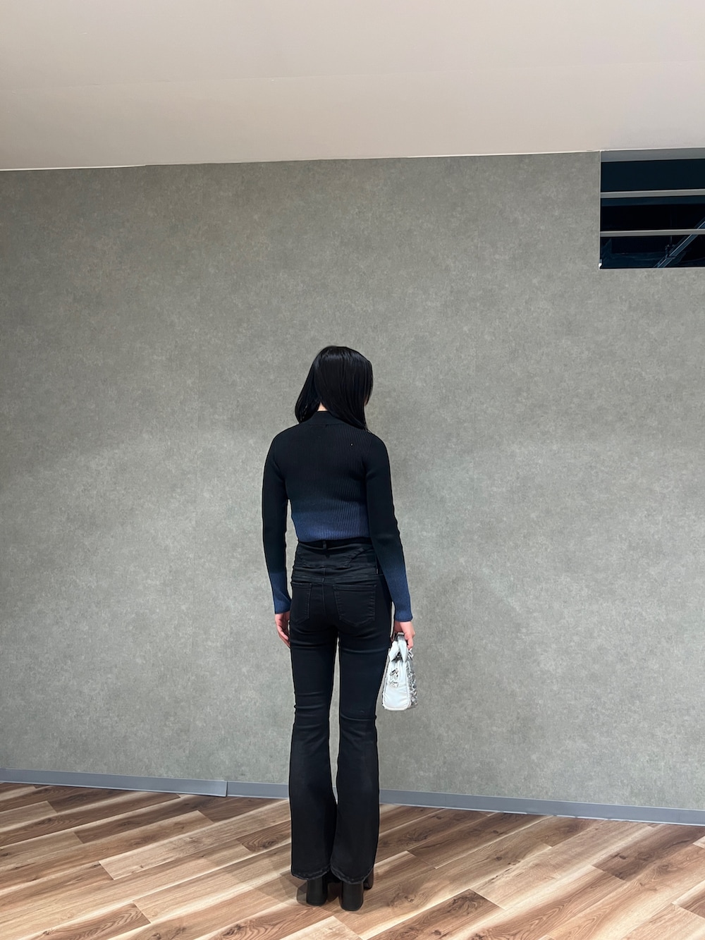 ブラック系のニット/セーター、ブラック系のデニムパンツ、ブラック系のブーツを着用したレディースの春コーディネートの3枚目の写真