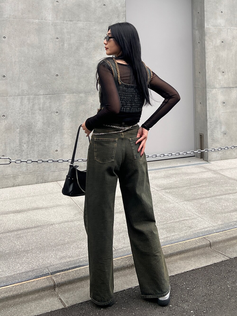 ブラック系のタンクトップ、ブルー系のデニムパンツ、シルバー系のスニーカーを着用したレディースの春コーディネートの2枚目の写真
