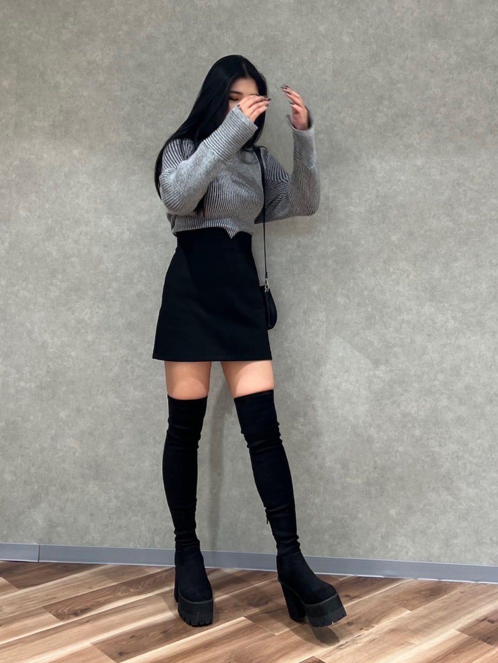 グレー系のニット/セーター、ブラック系のスカート、ブラック系のブーツを着用したレディースの秋コーディネートの3枚目の写真