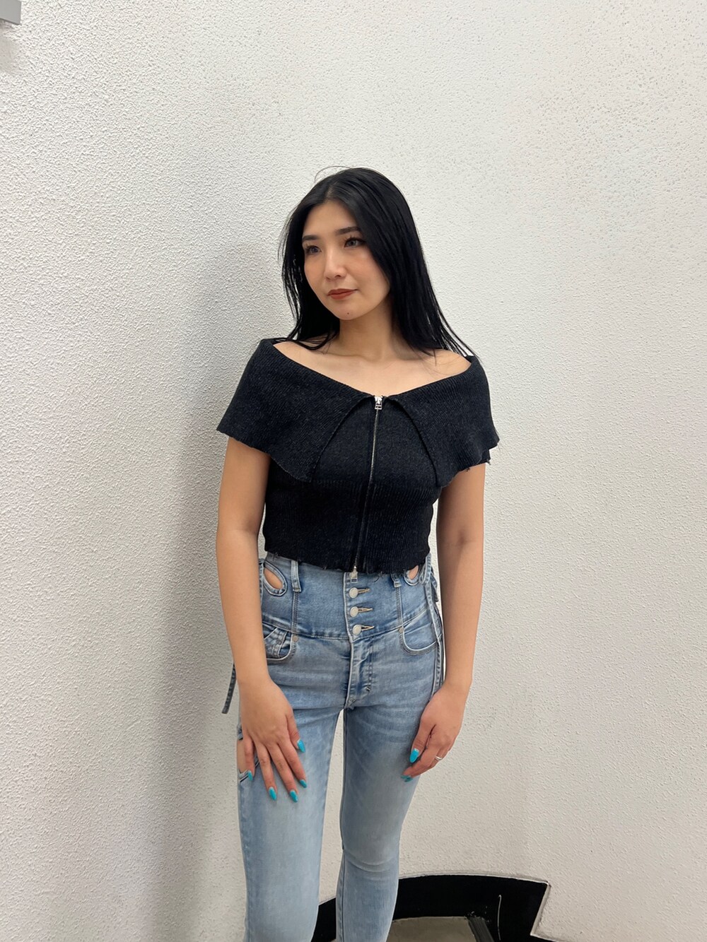 ブラック系のニット/セーター、ブルー系のデニムパンツ、ブラック系のサンダルを着用したレディースの春コーディネートの5枚目の写真