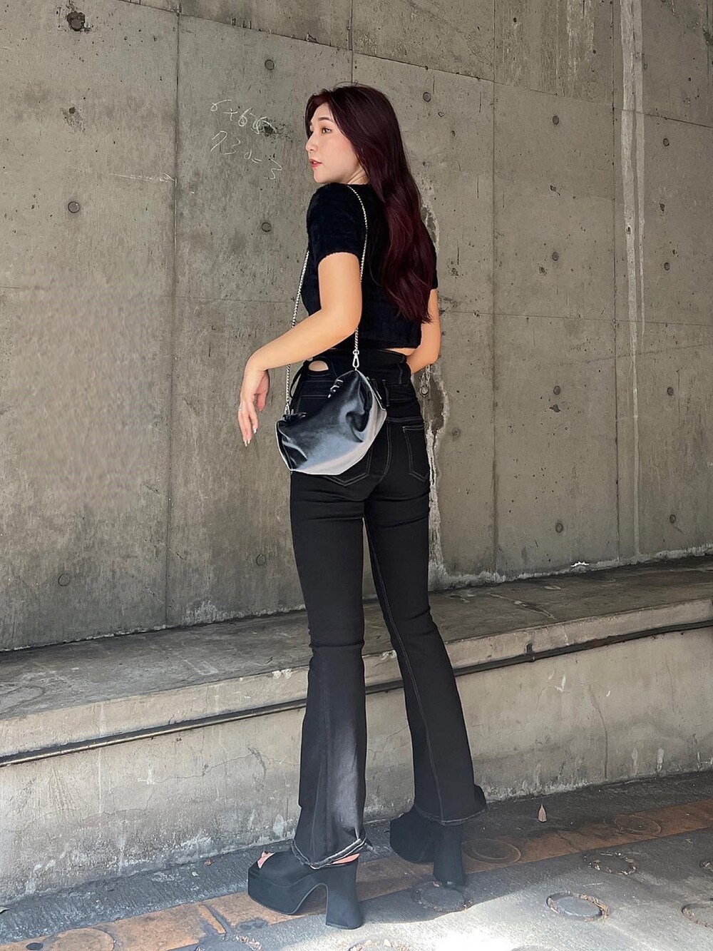 ブラック系のニット/セーター、ブラック系のデニムパンツ、グレー系のハンドバッグを着用したレディースの夏コーディネートの3枚目の写真