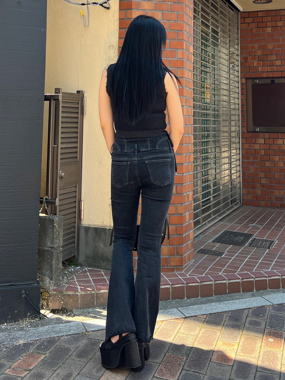 ブラック系のタンクトップ、ブラック系のデニムパンツ、ブラック系のサンダルを着用したレディースの春コーディネートの3枚目の写真