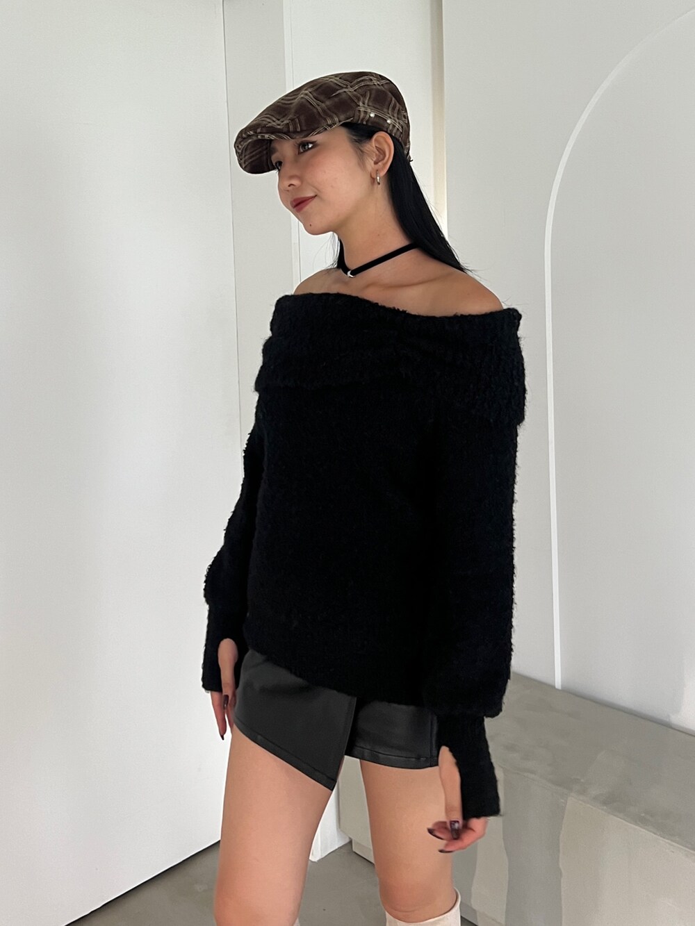 ブラック系のニット/セーター、ブラック系のスカート、ホワイト系のブーツを着用したレディースの秋コーディネートの5枚目の写真