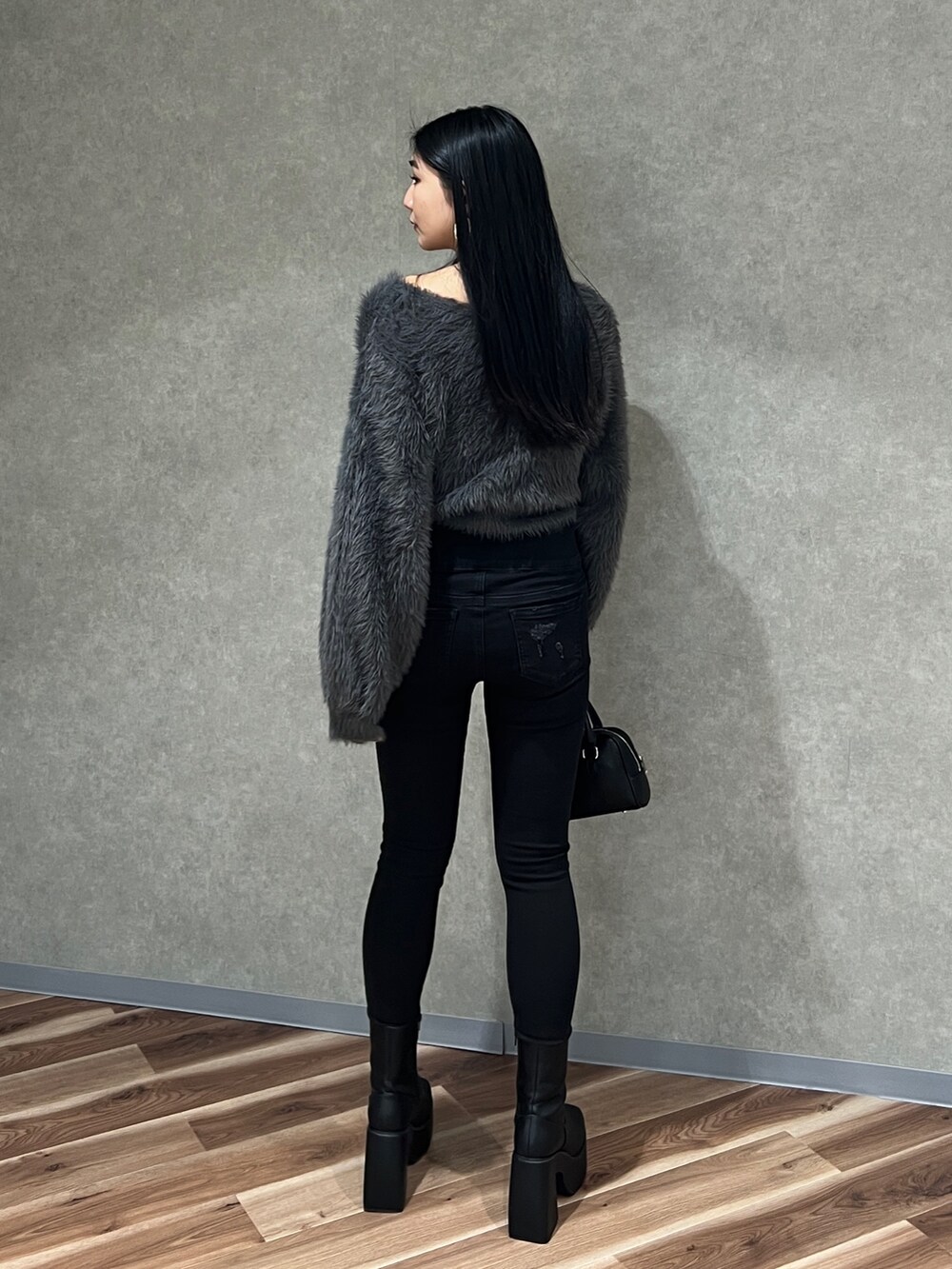 グレー系のニット/セーター、ブラック系のデニムパンツ、ブラック系のブーツを着用したレディースの秋コーディネートの4枚目の写真