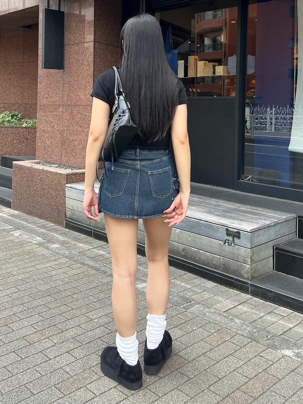 ブラック系のニット/セーター、ブルー系のスカート、ブラック系のその他シューズを着用したレディースの春コーディネートの4枚目の写真