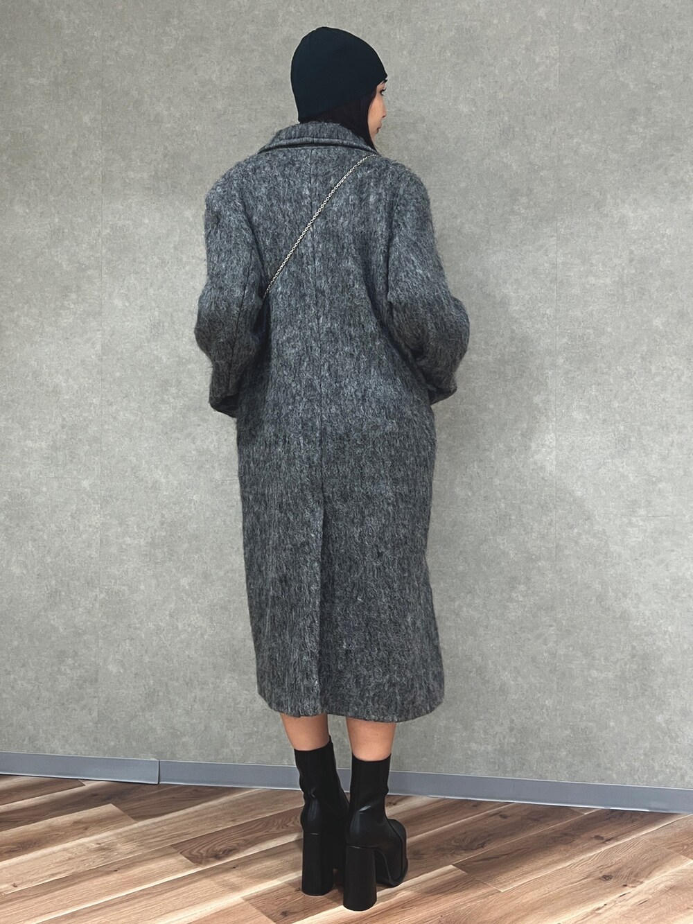 グレー系のチェスターコート、ブラック系のブーツ、ブラック系のニット/セーターを着用したレディースの冬コーディネートの3枚目の写真