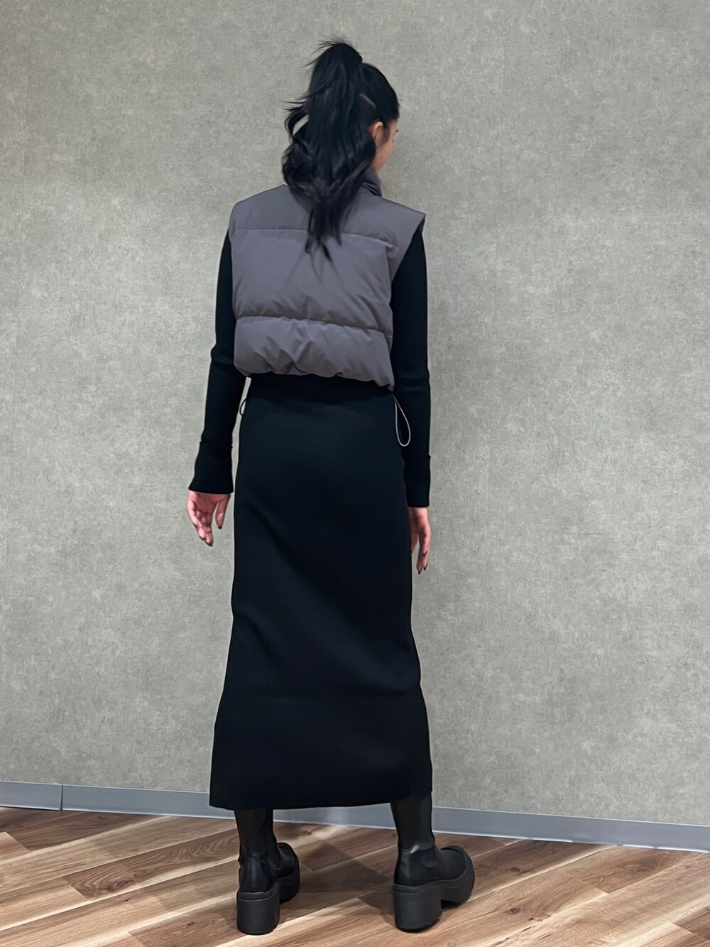 ブラック系のワンピース、グレー系のダウンベスト、ブラック系のブーツを着用したレディースの秋コーディネートの4枚目の写真