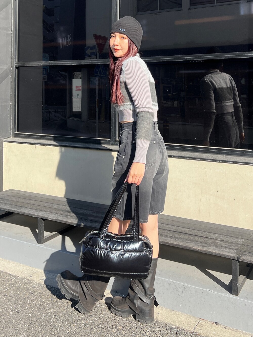 ブラック系のデニムパンツ、ブラック系のブーツ、シルバー系のボストンバッグを着用したレディースの冬コーディネートの3枚目の写真