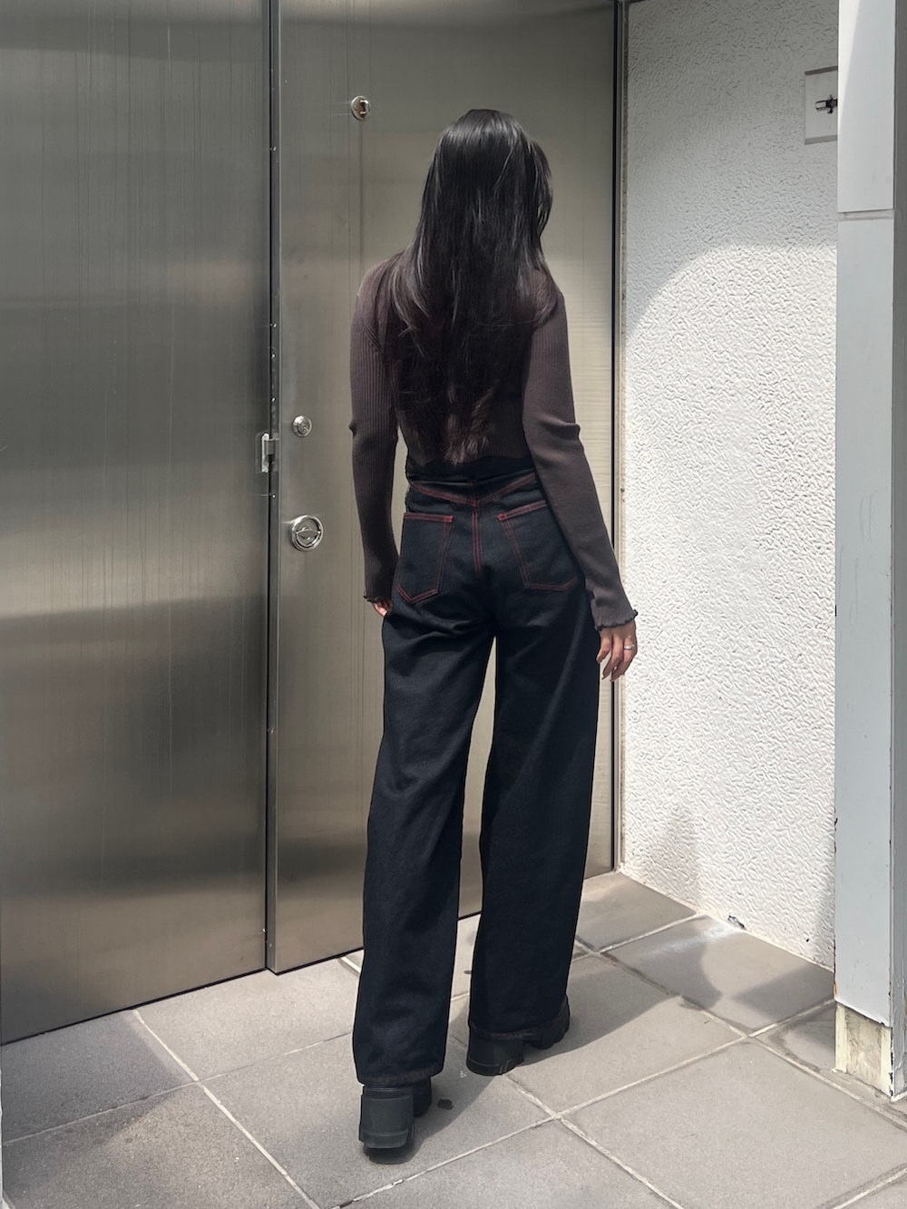 グリーン系のニット/セーター、ブルー系のデニムパンツ、ブラック系のブーツを着用したレディースの秋コーディネートの3枚目の写真