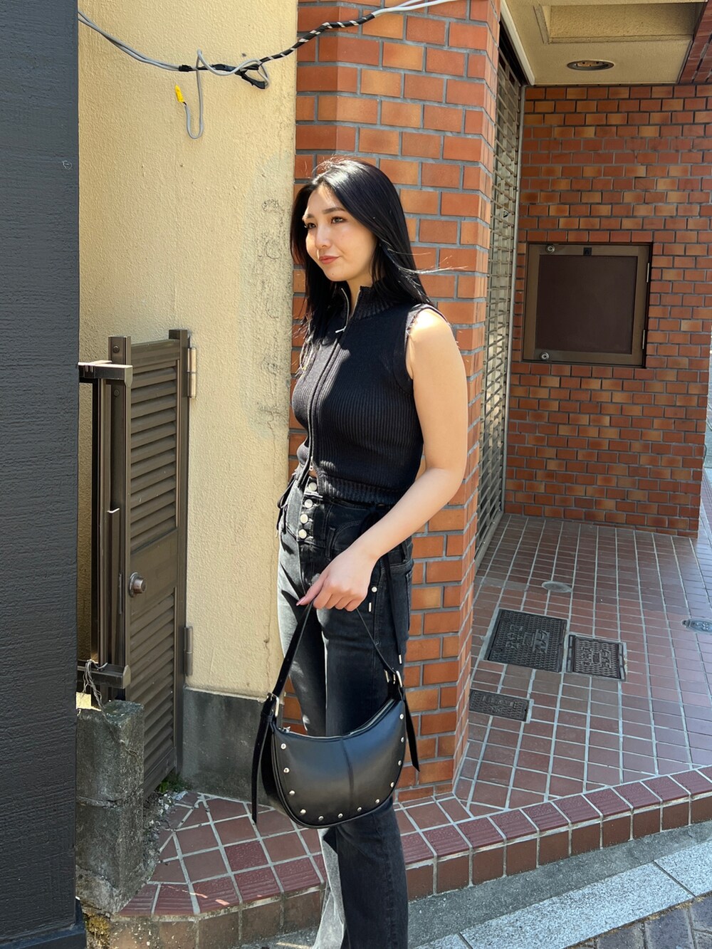 ブラック系のタンクトップ、ブラック系のデニムパンツ、ブラック系のサンダルを着用したレディースの春コーディネートの4枚目の写真