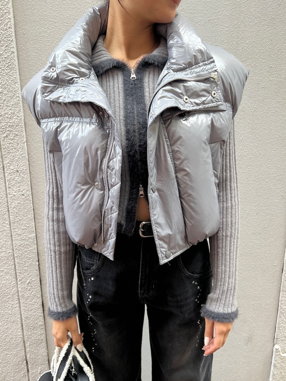 ブラック系のブーツ、ブラック系のハンドバッグ、グレー系のダウンベストを着用したレディースの秋コーディネートの4枚目の写真