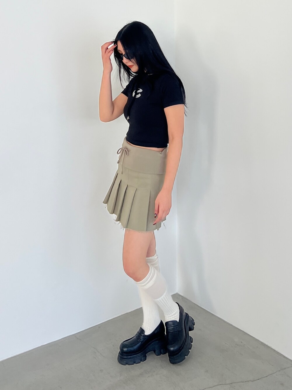 ベージュ系のスカート、ブラック系のローファー、ブラック系のTシャツ/カットソーを着用したレディースの春コーディネートの2枚目の写真