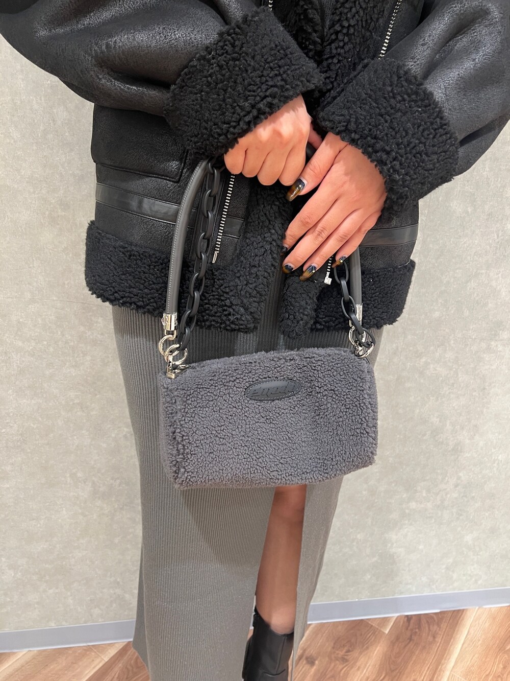 ブラック系のムートンコート、グレー系のワンピース、グレー系のハンドバッグを着用したレディースの秋コーディネートの5枚目の写真