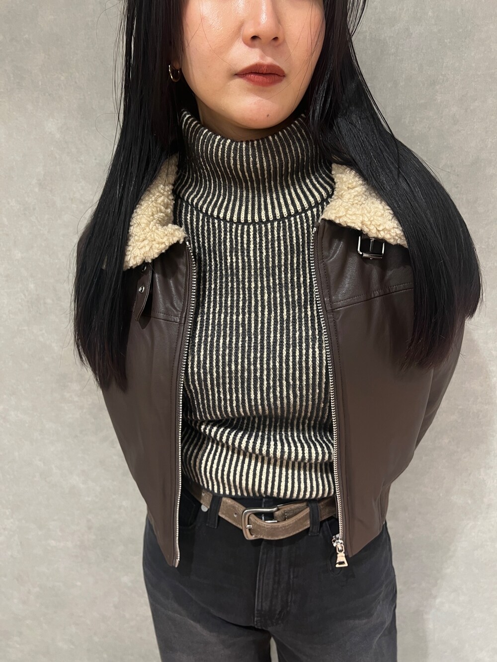 ブラウン系のブルゾン、ブラック系のニット/セーター、ブラック系のデニムパンツを着用したレディースの秋コーディネートの5枚目の写真