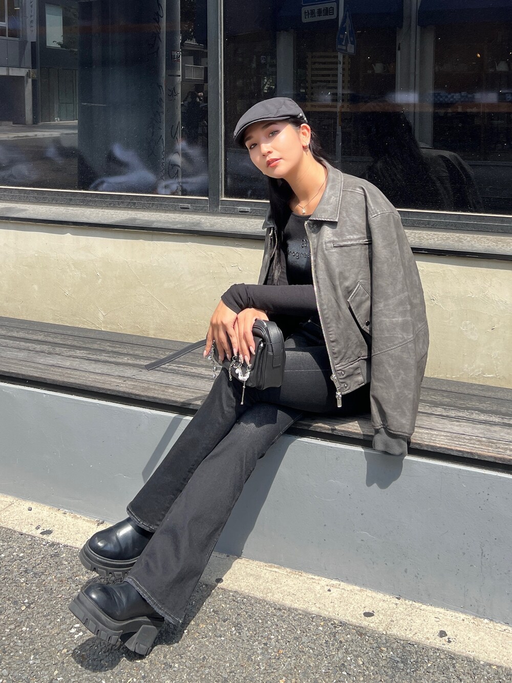 グレー系のブルゾン、ブラック系のデニムパンツ、ブラック系のブーツを着用したレディースの秋コーディネートの4枚目の写真