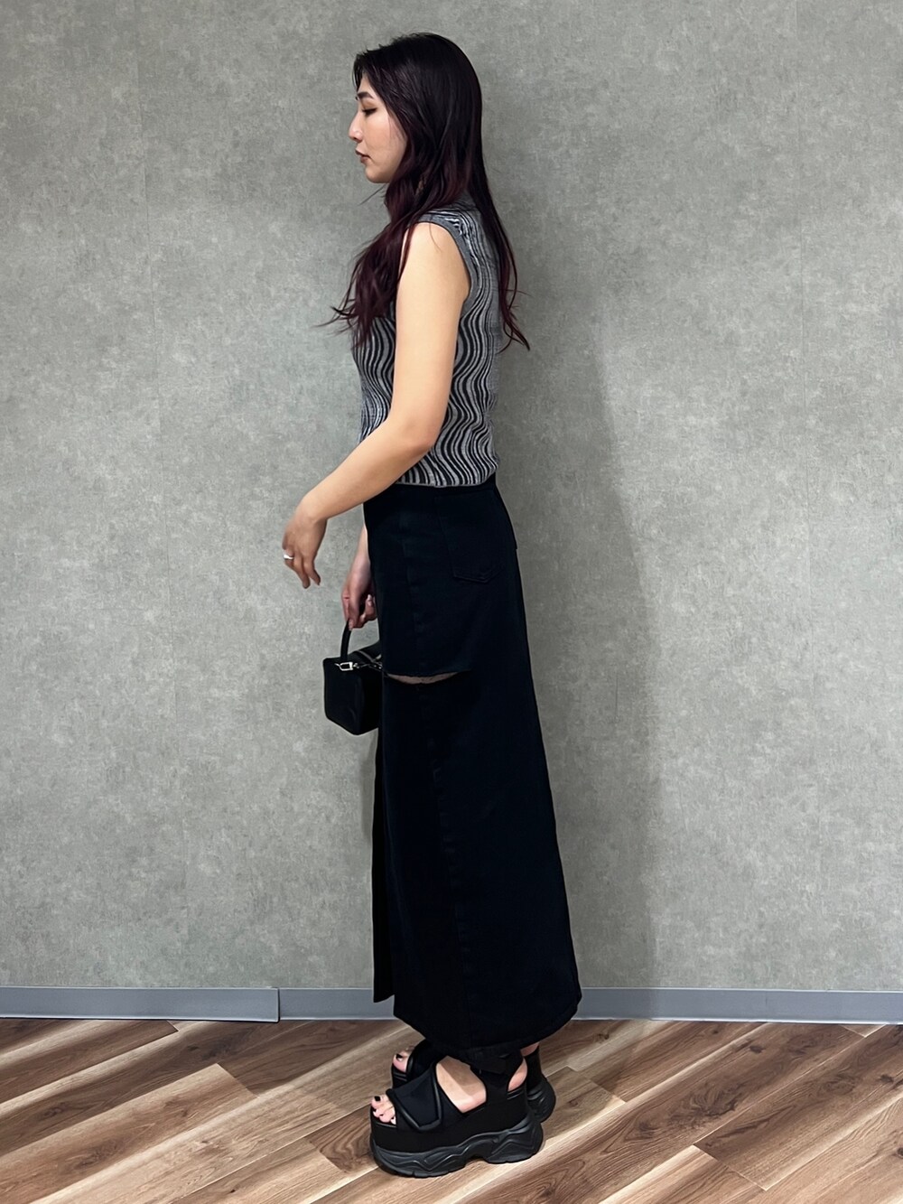 グレー系のタンクトップ、ブラック系のデニムスカート、ブラック系のハンドバッグを着用したレディースの夏コーディネートの4枚目の写真