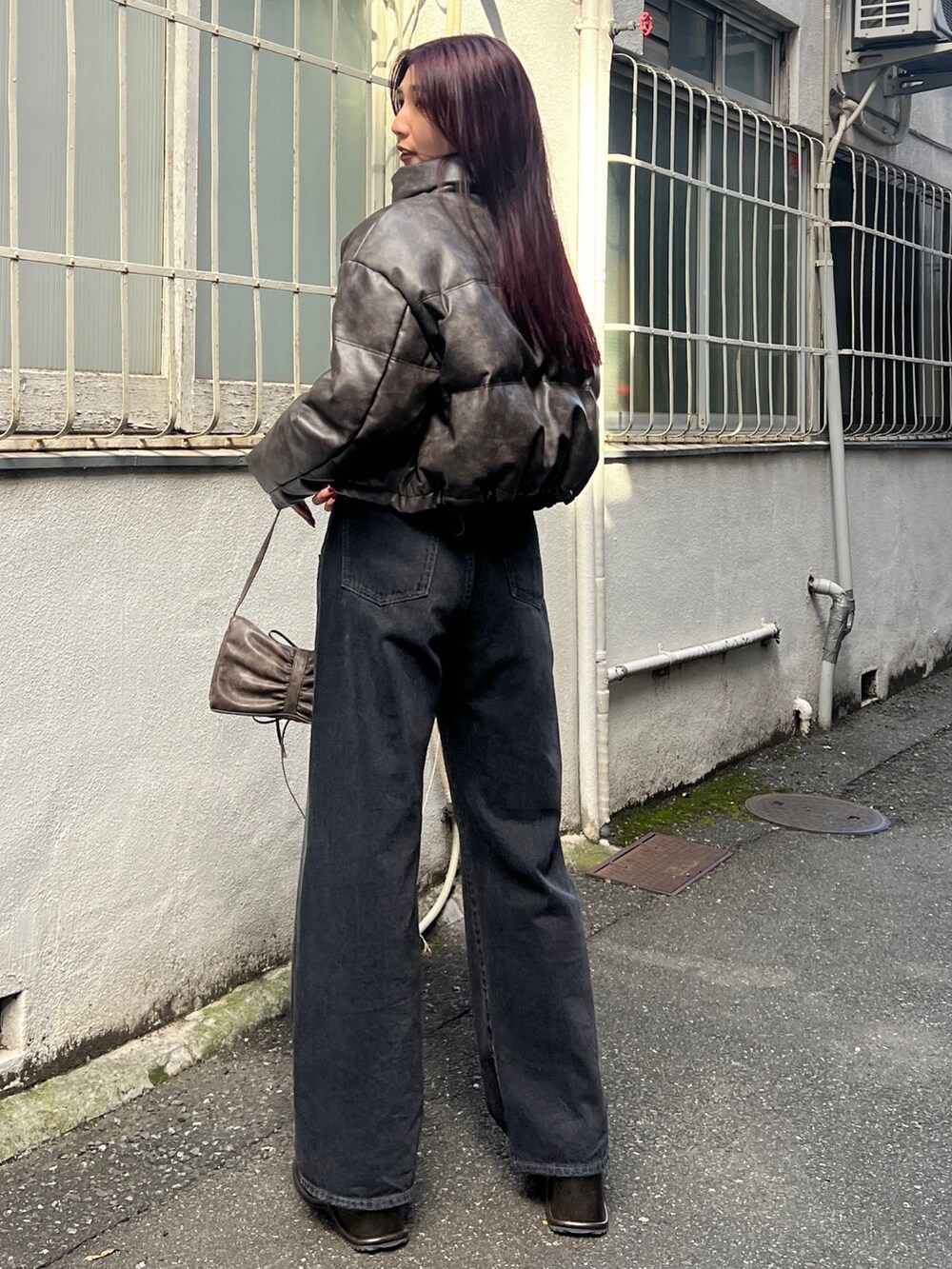 ブラウン系のダウンジャケット/コート、ブラック系のニット/セーター、ブラック系のデニムパンツを着用したレディースの秋コーディネートの3枚目の写真