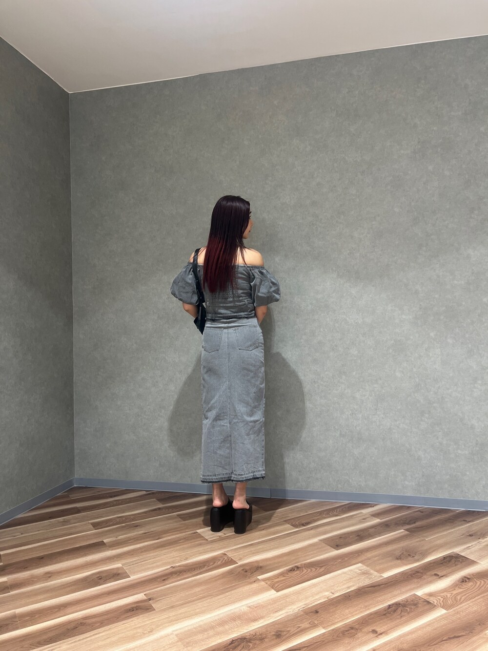 ブラック系のサンダル、グレー系のスカート、ブラック系のハンドバッグを着用したレディースの春コーディネートの3枚目の写真