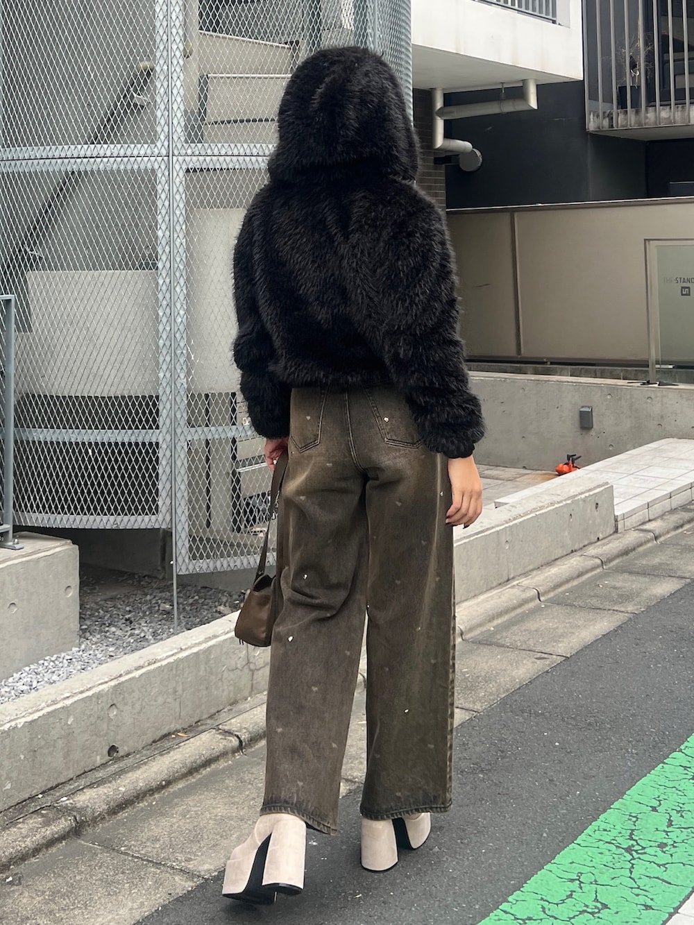 ブラック系のブルゾン、ブラック系のニット/セーター、ブラウン系のデニムパンツを着用したレディースの秋コーディネートの3枚目の写真