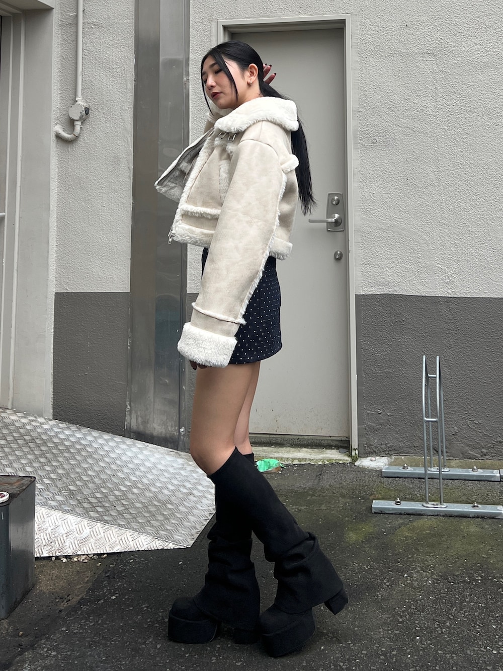 ホワイト系のブルゾン、ブルー系のスカート、ブラック系のブーツを着用したレディースの秋コーディネートの2枚目の写真