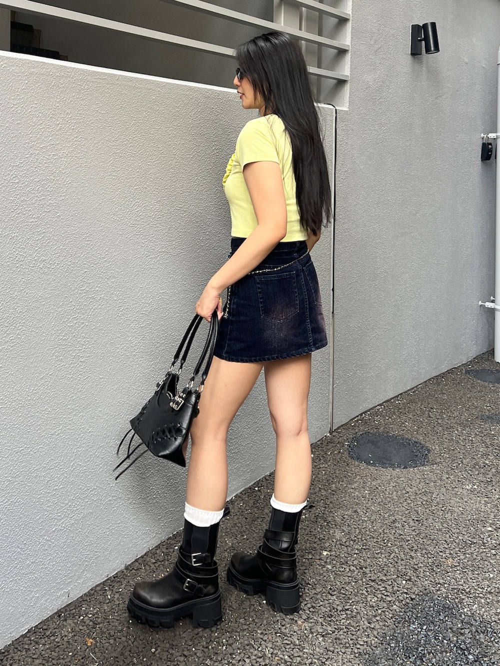 イエロー系のTシャツ/カットソー、ブルー系のスカート、ブラック系のブーツを着用したレディースの夏コーディネートの3枚目の写真