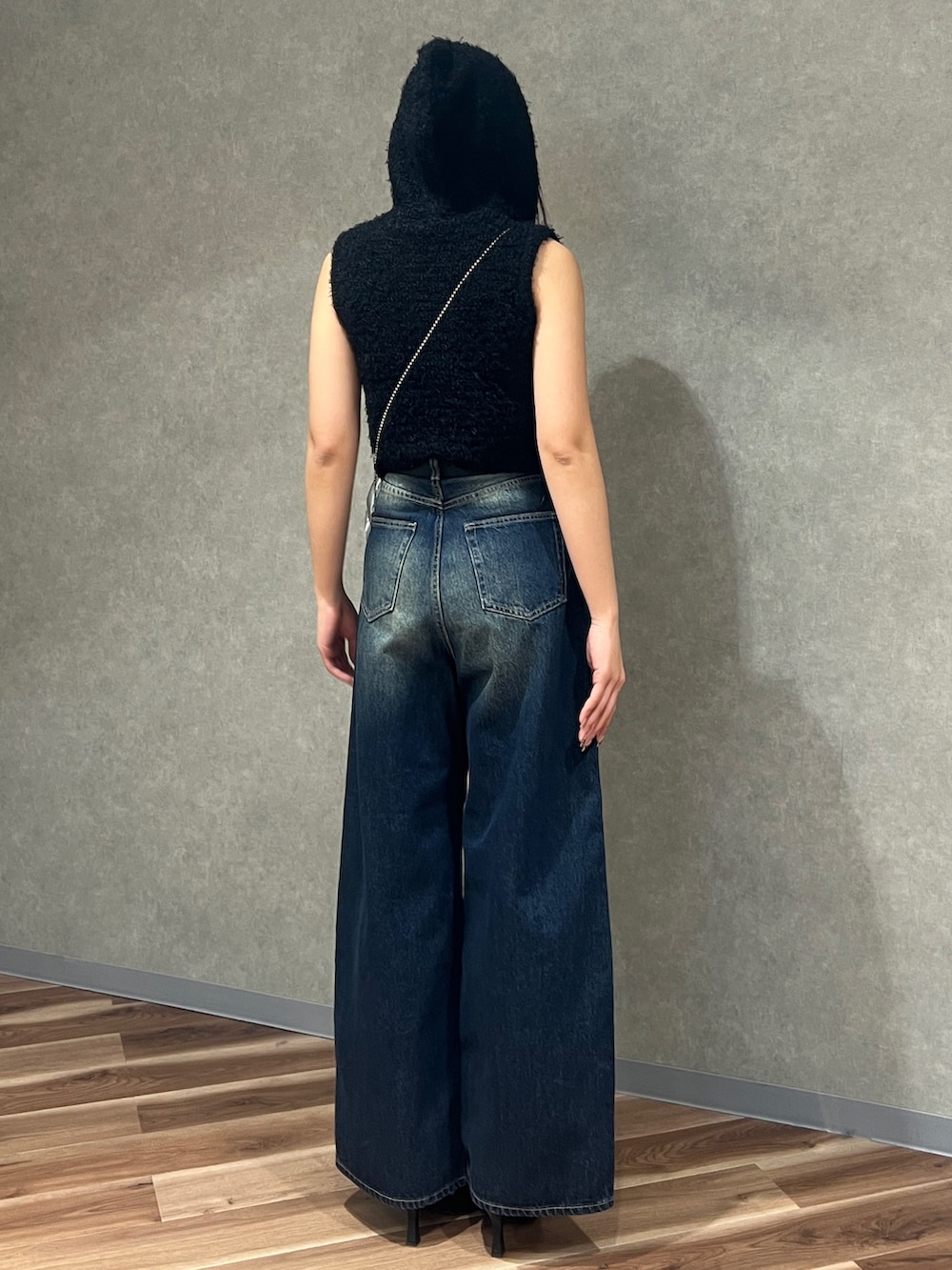 ブラック系のニット/セーター、ブルー系のデニムパンツ、ブラック系のパンプスを着用したレディースの春コーディネートの3枚目の写真