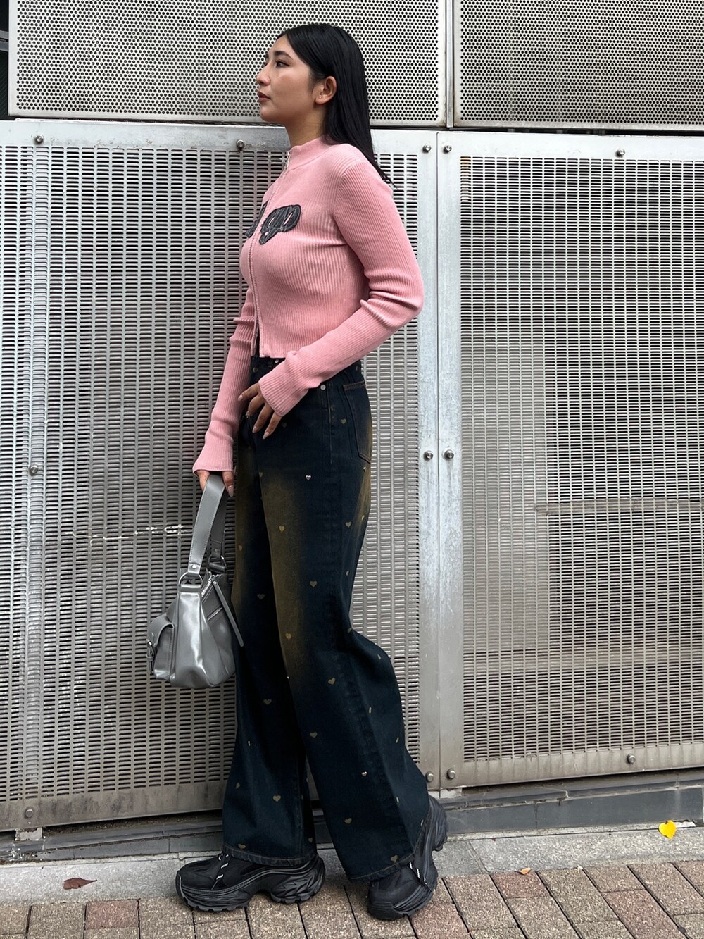 ピンク系のニット/セーター、ブルー系のデニムパンツ、ブラック系のスニーカーを着用したレディースの秋コーディネートの2枚目の写真