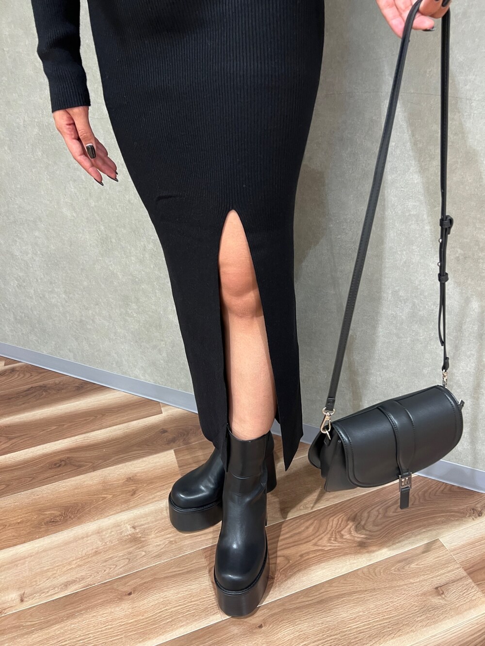 ブラック系のニット/セーター、ブラック系のスカート、ブラック系のブーツを着用したレディースの秋コーディネートの7枚目の写真