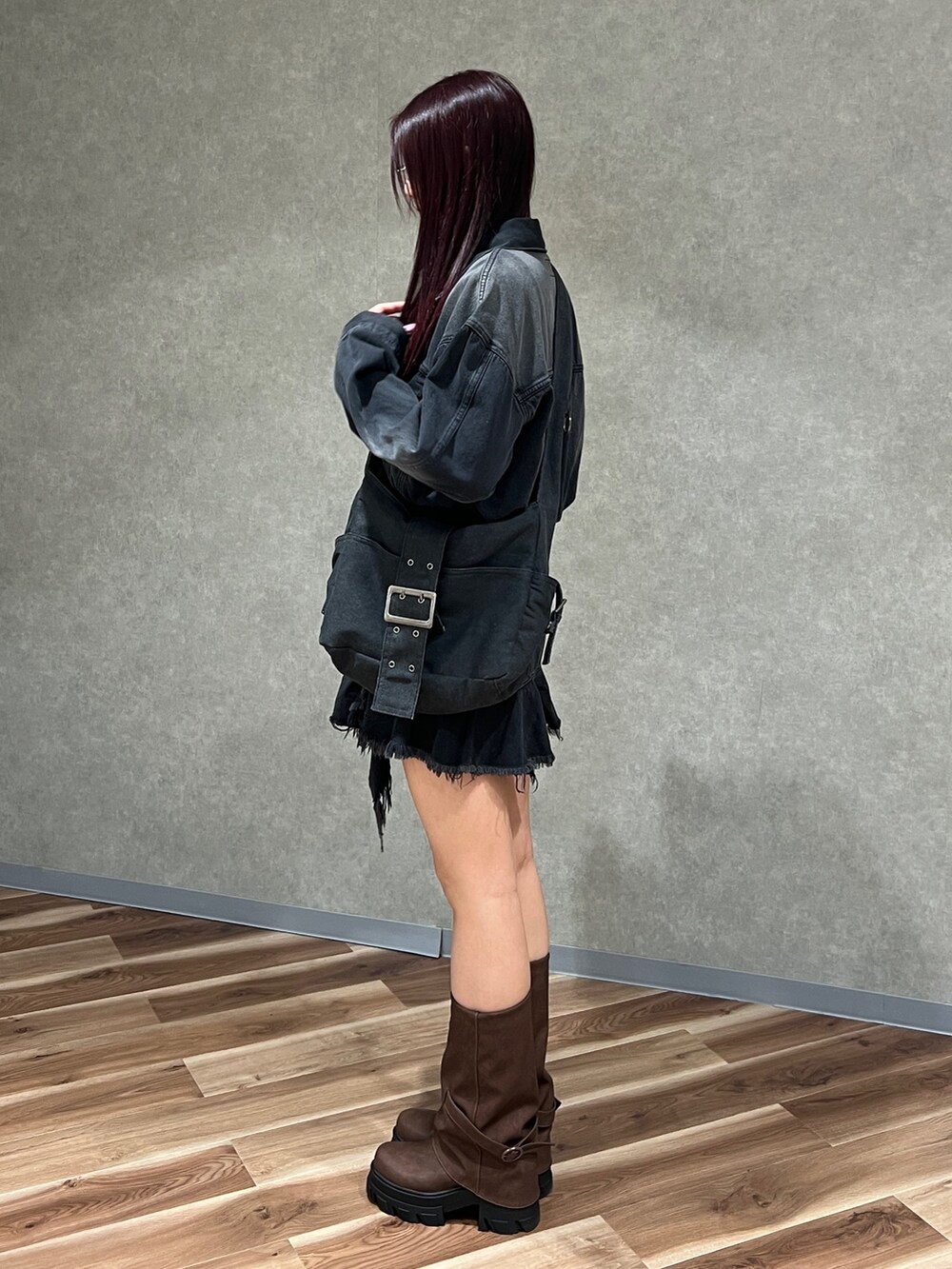 ブラック系のワンピース、ブラック系のデニムジャケット、ブラウン系のブーツを着用したレディースの冬コーディネートの3枚目の写真