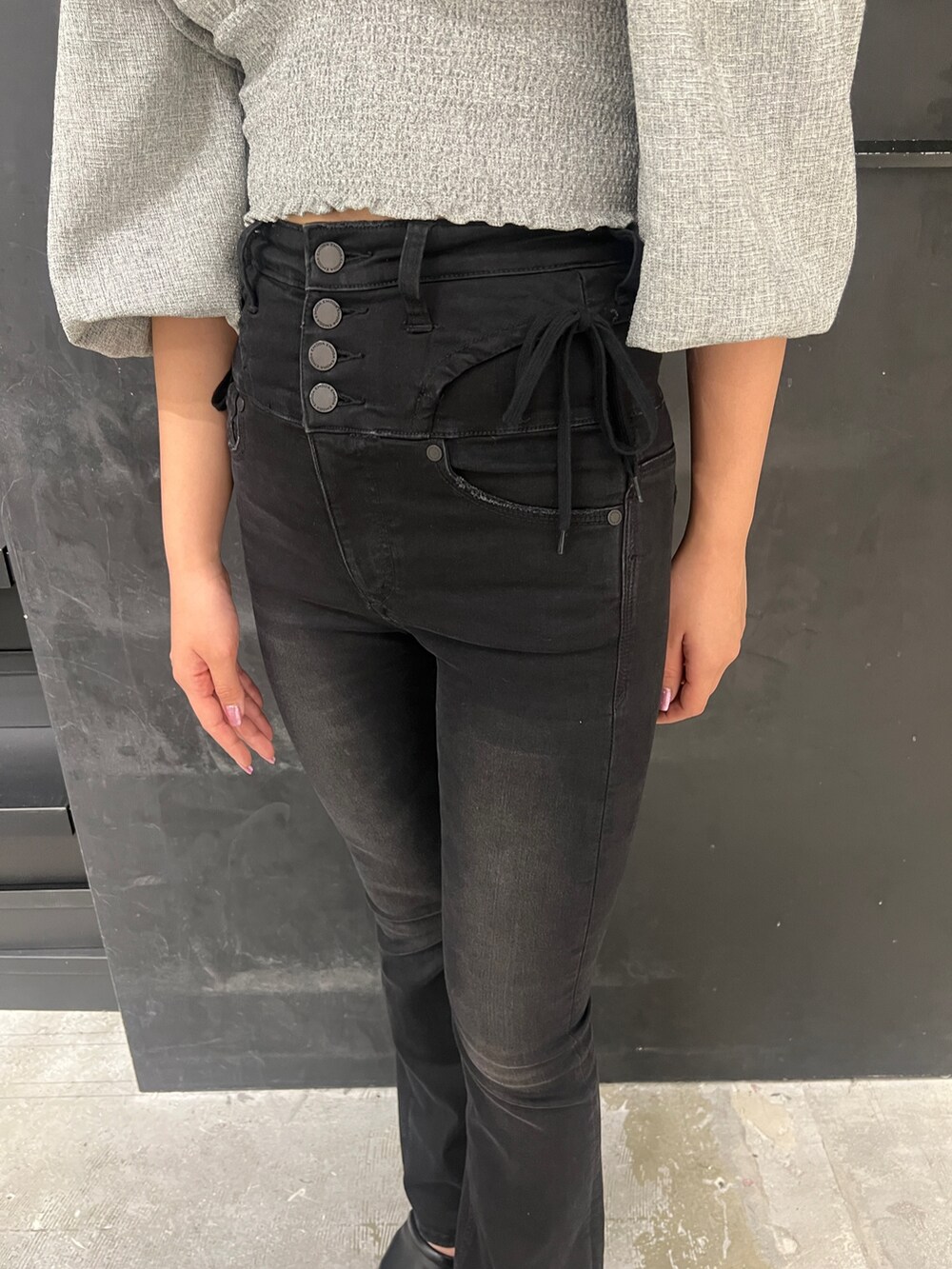 ブラック系のデニムパンツ、ブラック系のサンダル、グレー系のTシャツ/カットソーを着用したレディースの春コーディネートの5枚目の写真