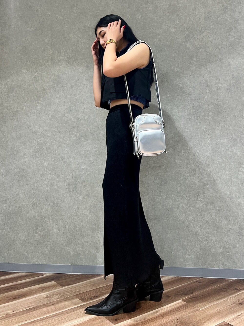 ブラック系のスカート、シルバー系のショルダーバッグ、ブラック系のブーツを着用したレディースの夏コーディネートの3枚目の写真
