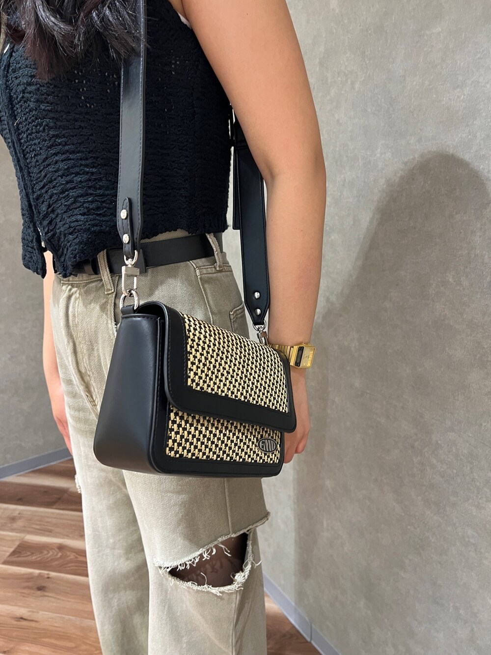 ブラック系のベスト、ホワイト系のニット/セーター、ベージュ系のデニムパンツを着用したレディースの夏コーディネートの5枚目の写真