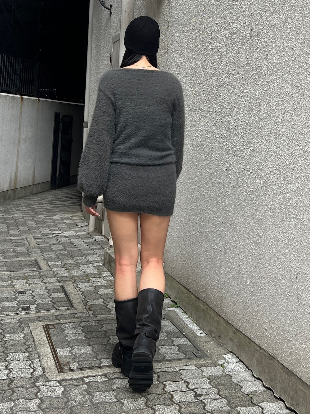 グレー系のワンピース、ブラック系のブーツ、ブラック系のニットキャップ/ビーニーを着用したレディースの冬コーディネートの2枚目の写真