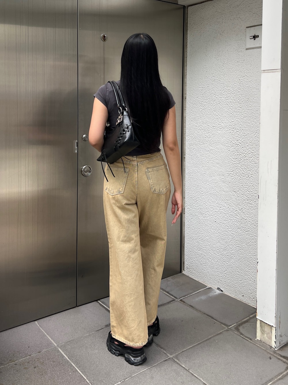 ブラック系のTシャツ/カットソー、ベージュ系のデニムパンツ、ブラック系のサンダルを着用したレディースの夏コーディネートの3枚目の写真