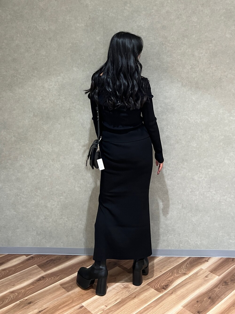 ブラック系のニット/セーター、ブラック系のスカート、ブラック系のブーツを着用したレディースの秋コーディネートの6枚目の写真