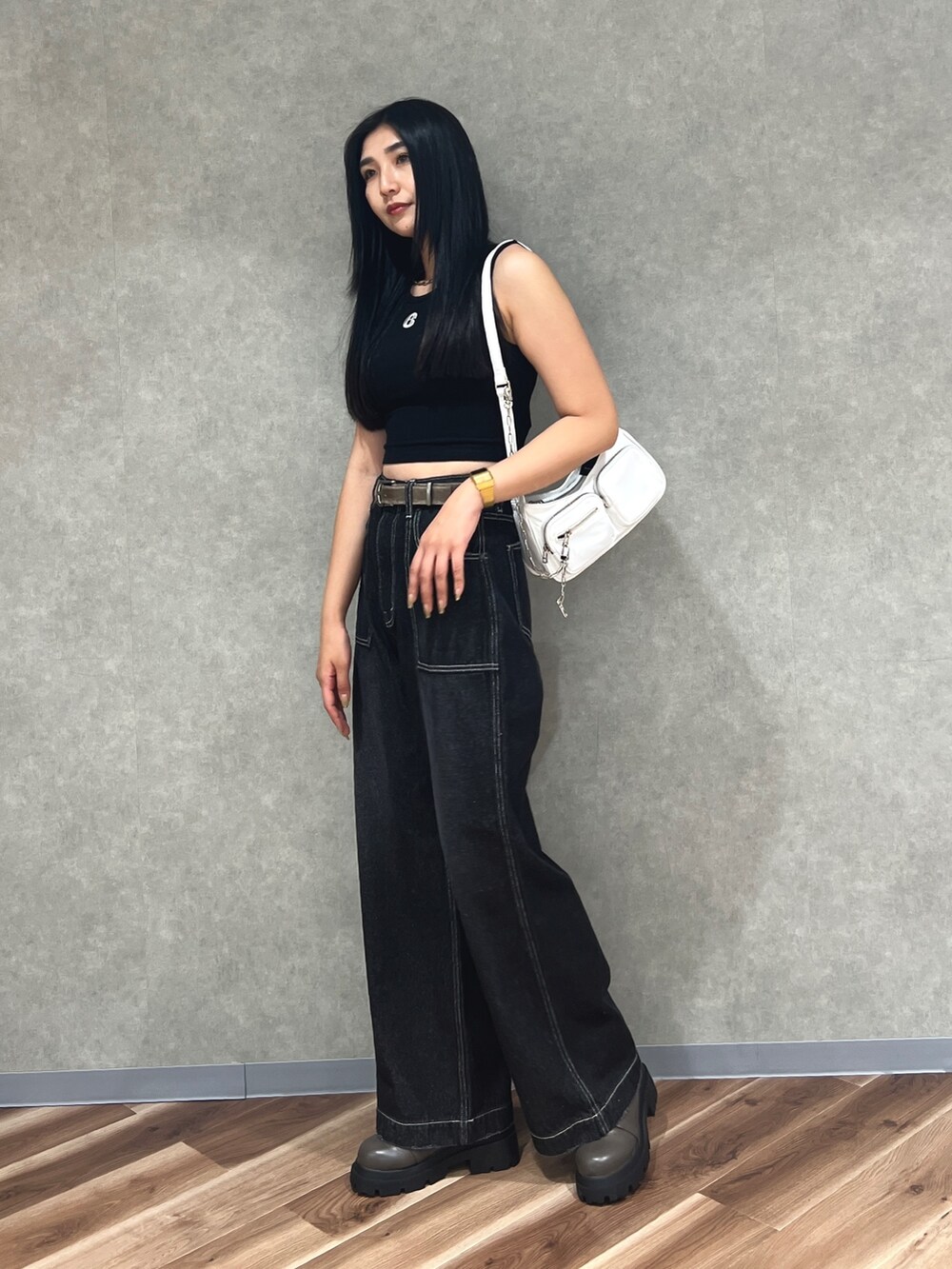 ブラック系のタンクトップ、ブルー系のデニムパンツ、ホワイト系のハンドバッグを着用したレディースの夏コーディネートの2枚目の写真