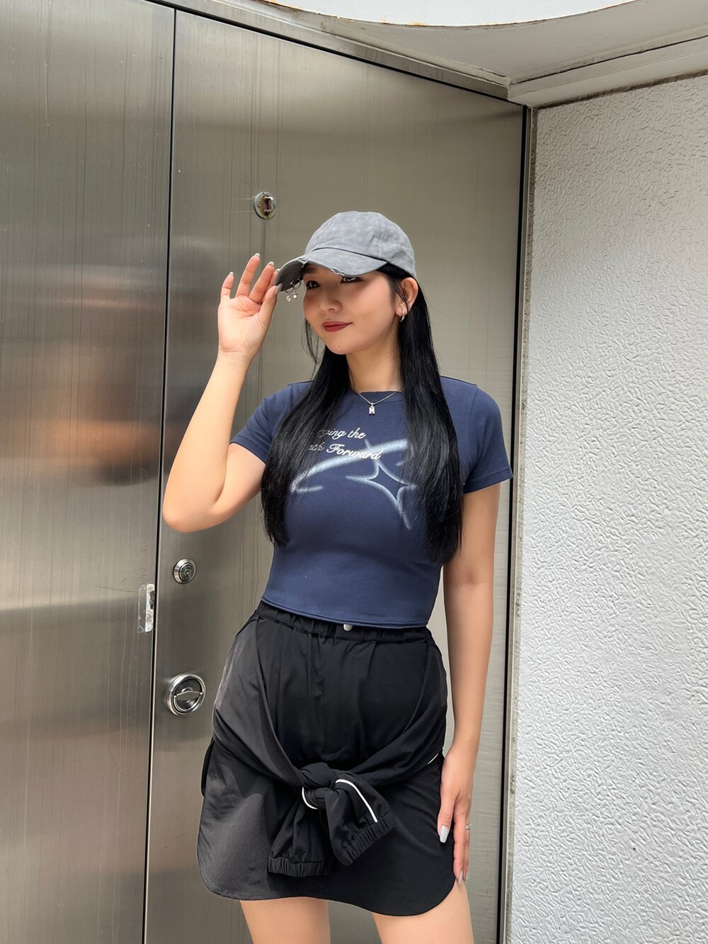 ブルー系のTシャツ/カットソー、ブラック系のスカート、ブラック系のスニーカーを着用したレディースの夏コーディネートの3枚目の写真