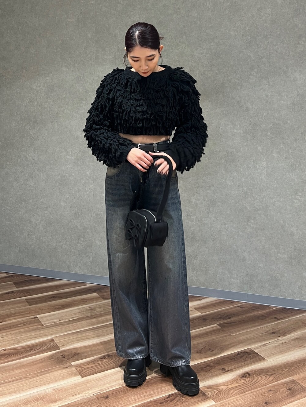 ブラック系のニット/セーター、ブルー系のデニムパンツ、ブラック系のブーツを着用したレディースの冬コーディネートの2枚目の写真