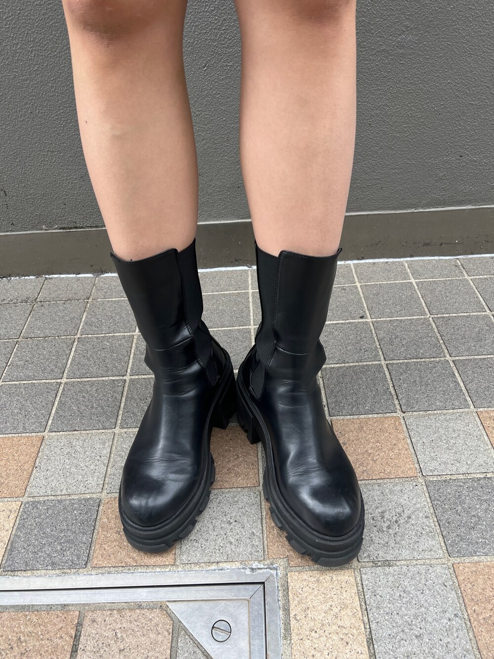 ブラック系のスカート、ブラック系のブーツ、ブラック系のハンドバッグを着用したレディースの春コーディネートの5枚目の写真