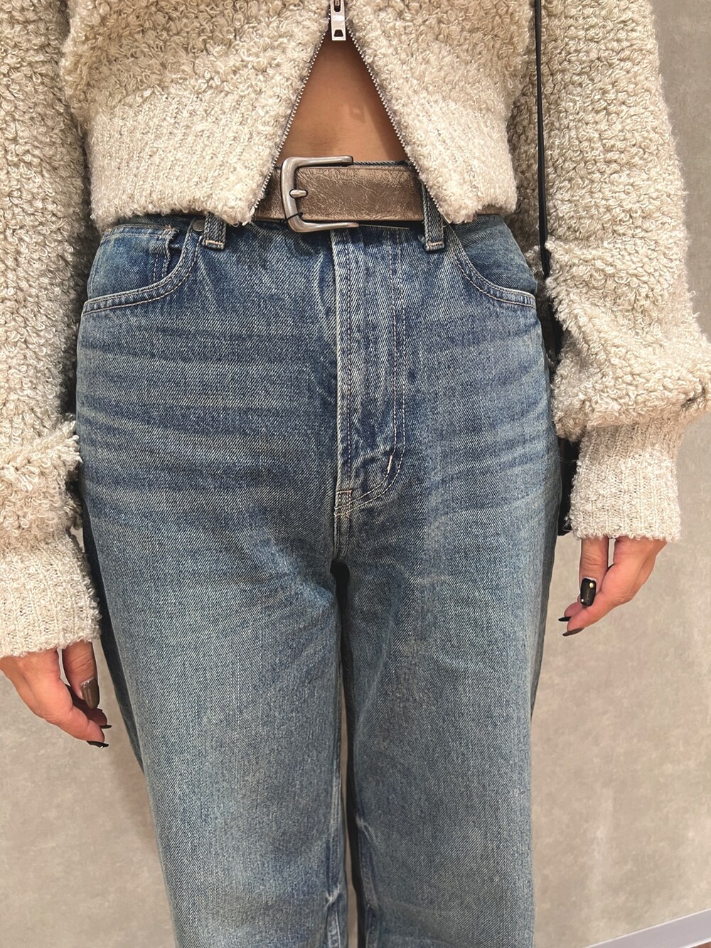 グレー系のニット/セーター、ブルー系のデニムパンツ、ホワイト系のブーツを着用したレディースの秋コーディネートの7枚目の写真