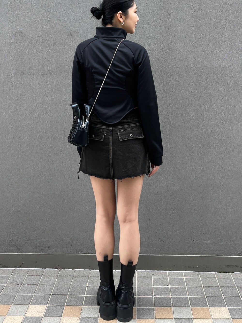 ブラック系のスカート、ブラック系のブーツ、ブラック系のハンドバッグを着用したレディースの春コーディネートの3枚目の写真