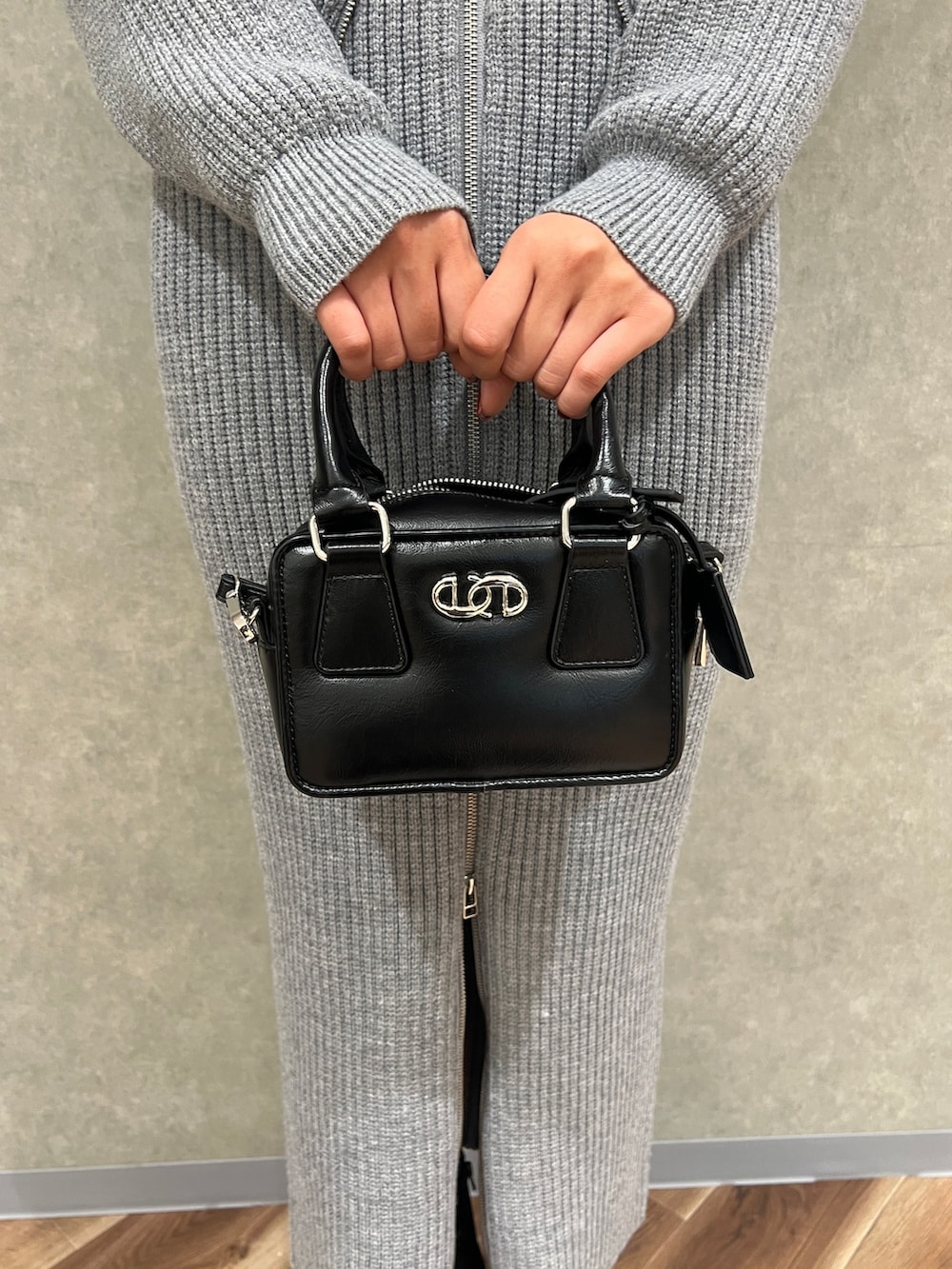 グレー系のスカート、グレー系のニット/セーター、ブラック系のブーツを着用したレディースの冬コーディネートの7枚目の写真