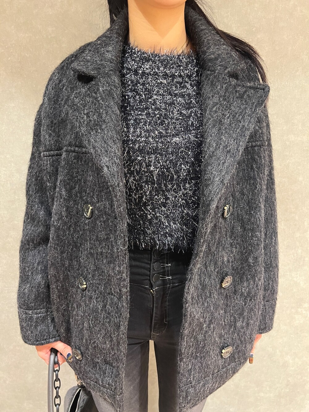 グレー系のピーコート、ブラック系のニット/セーター、ブラック系のデニムパンツを着用したレディースの秋コーディネートの5枚目の写真