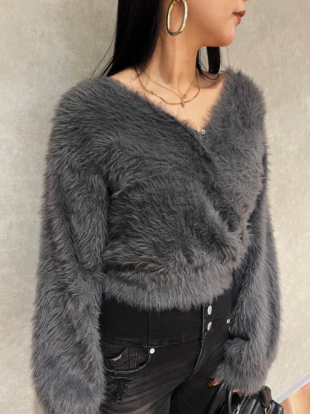 グレー系のニット/セーター、ブラック系のデニムパンツ、ブラック系のブーツを着用したレディースの秋コーディネートの5枚目の写真